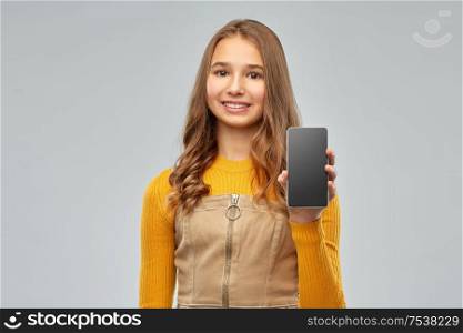 technology, communication and people concept - smiling teenage girl showing blank screen of smartphone over grey background. smiling teenage girl showing smartphone