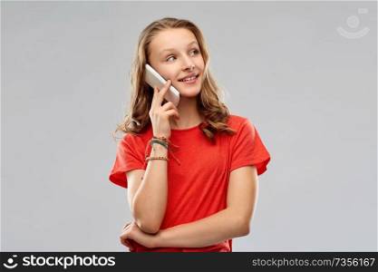 technology, communication and people concept - smiling teenage girl with long hair in red t-shirt calling on smartphone over grey background. smiling teenage girl calling on smartphone