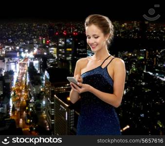 technology, communication and people concept - smiling woman in evening dress holding smartphone over night city background