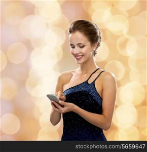 technology, communication and people concept - smiling woman in evening dress holding smartphone over holidays lights background