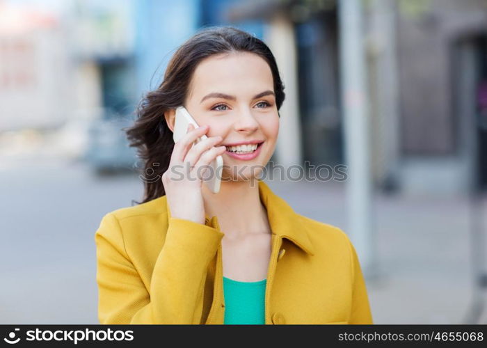 technology, communication and people concept - smiling young woman or girl calling on smartphone on city street