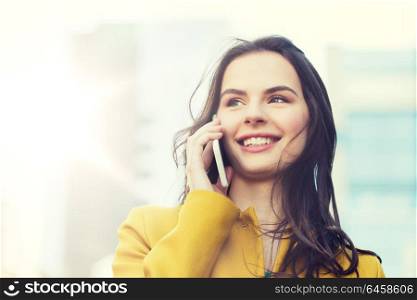 technology, communication and people concept - smiling young woman or girl calling on smartphone on city street. smiling young woman or girl calling on smartphone
