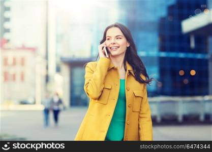 technology, communication and people concept - smiling young woman or girl calling on smartphone on city street. smiling young woman or girl calling on smartphone. smiling young woman or girl calling on smartphone
