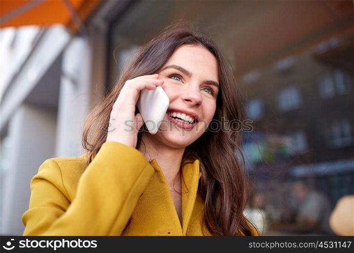 technology, communication and people concept - smiling young woman or teenage girl calling on smartphone and walking along on city street