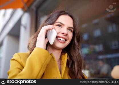 technology, communication and people concept - smiling young woman or teenage girl calling on smartphone and walking along on city street