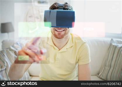 technology, communication, entertainment and people concept - happy young man in virtual reality headset or 3d glasses receiving incoming call at home