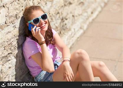 technology, communication, lifestyle and people concept - smiling young woman or teenage girl calling on smartphone on summer city street. happy young woman or girl calling on smartphone