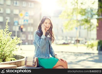 technology, communication, lifestyle and people concept - smiling young woman or teenage girl calling on smartphone on city street. happy young woman or girl calling on smartphone