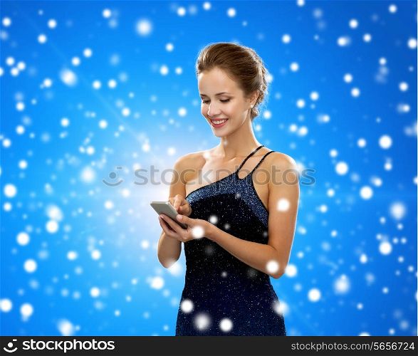 technology, communication, winter holidays, christmas and people concept - smiling woman in evening dress holding smartphone over blue snowy background