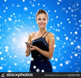 technology, communication, winter holidays, christmas and people concept - smiling woman in evening dress holding smartphone over blue snowy background