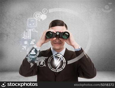 Technology concept. Businessman with biboculars and virtual interface with web and social media icons