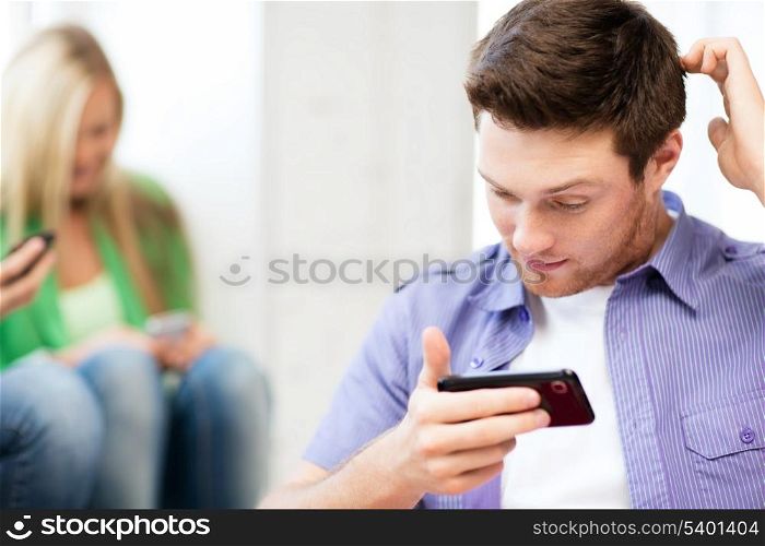 technology concept - student looking at phone and writing something