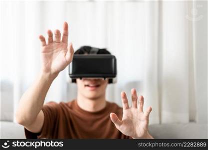 Technology Concept The man with his brown T-shirt and light blue jeans wearing a virtual reality headset while sitting on the sofa.