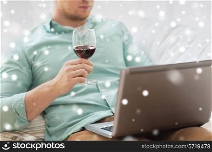 technology, drinks, leisure, home and lifestyle concept - close up of man with laptop and glass of wine at home