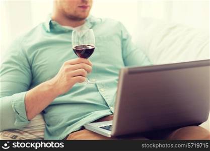 technology, drinks, leisure, home and lifestyle concept - close up of man close up of man with laptop and glass of wine at home