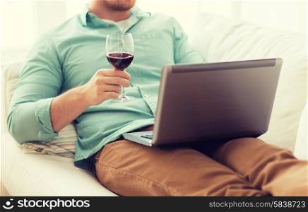 technology, drinks, leisure, home and lifestyle concept - close up of man close up of man with laptop and glass of wine at home