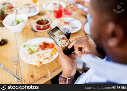technology, eating and people concept - hands with smartphone photographing food at restaurant. hands with smartphone picturing food at restaurant