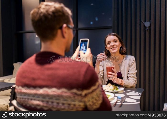 technology, eating, vegetarian food and people concept - happy man with smartphone photographing at vegan restaurant. happy couple having dinner at vegan restaurant