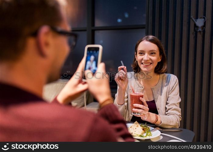 technology, eating, vegetarian food and people concept - happy man with smartphone photographing at vegan restaurant. happy couple with smartphone at vegan restaurant