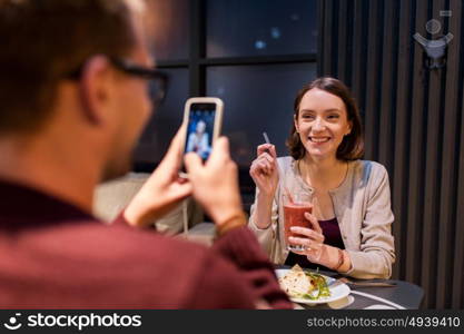 technology, eating, vegetarian food and people concept - happy man with smartphone photographing at vegan restaurant. happy couple with smartphone at vegan restaurant