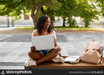 technology, education and people concept - happy smiling african american student girl with laptop computer and books in city. african student girl with laptop and books in city