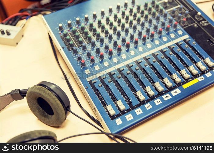 technology, electronics and equipment concept - control panel and headphones at recording studio or radio station