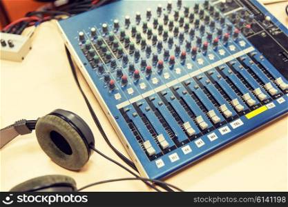 technology, electronics and equipment concept - control panel and headphones at recording studio or radio station