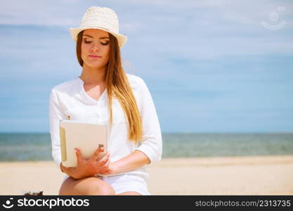 Technology enjoyment. Long haired beauty girl in straw hat with tablet e-book on beach. Student woman resting in summer on fresh air.. Girl with tablet on seaside.