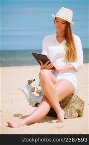 Technology enjoyment. Long haired beauty girl in straw hat with tablet e-book on beach. Student woman resting in summer on fresh air.. Girl with tablet on seaside.