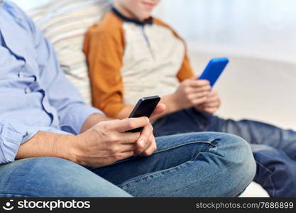 technology, family and people concept - close up of father and son with smartphones at home. father and son with smartphones at home