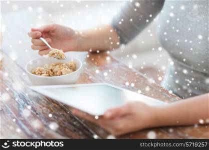 technology, food and home concept - close up of woman with to tablet pc computer screen sitting at table and eating breakfast at home