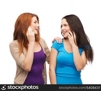 technology, friendship and leirure concept - two smiling teenagers talking with smartphones