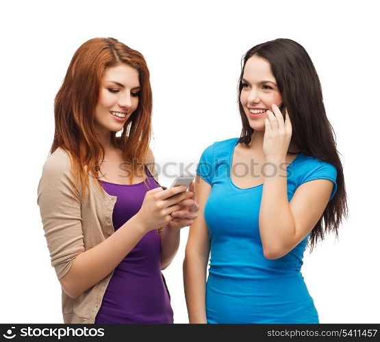 technology, friendship and leirure concept - two smiling teenagers with smartphones texting and calling