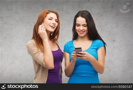 technology, friendship and leisure concept - two smiling teenagers with smartphones texting and calling