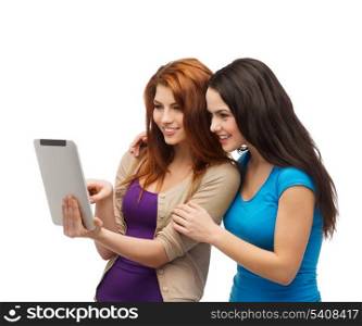 technology, friendship and people concept - two smiling teenagers pointing finger at tablet pc screen