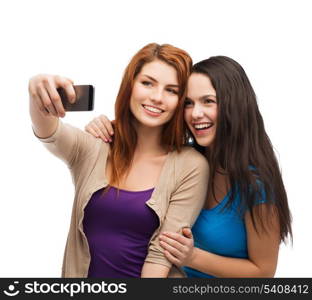 technology, friendship and people concept - two smiling teenagers taking picture with smartphone camera