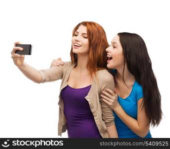 technology, friendship and people concept - two smiling teenagers taking picture with smartphone camera