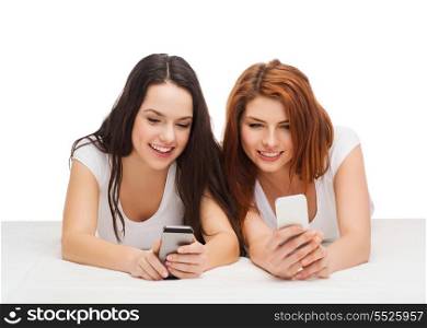 technology, friendship and people concept - two smiling teenagers with smartphones