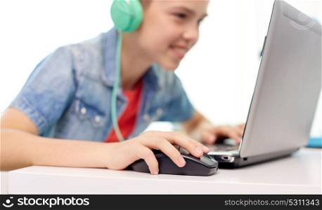 technology, gaming and people concept - close up of boy in headphones playing video game on laptop computer at home. boy in headphones playing video game on laptop