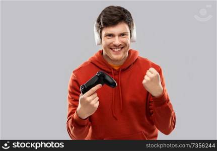 technology, gaming and people concept - young man or gamer in headphones with gamepad playing video game. man with gamepad playing video game