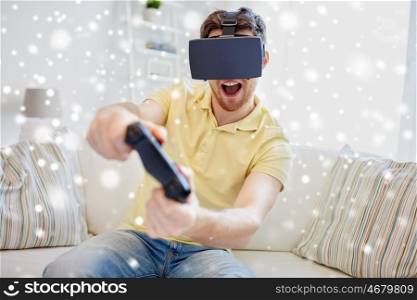 technology, gaming, augmented reality, entertainment and people concept - happy young man with virtual headset or 3d glasses with controller gamepad playing racing video game at home over snow