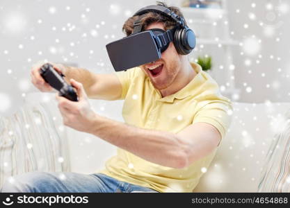 technology, gaming, augmented reality, entertainment and people concept - young man in headphones with virtual headset or 3d glasses with controller gamepad playing racing video game at home over snow