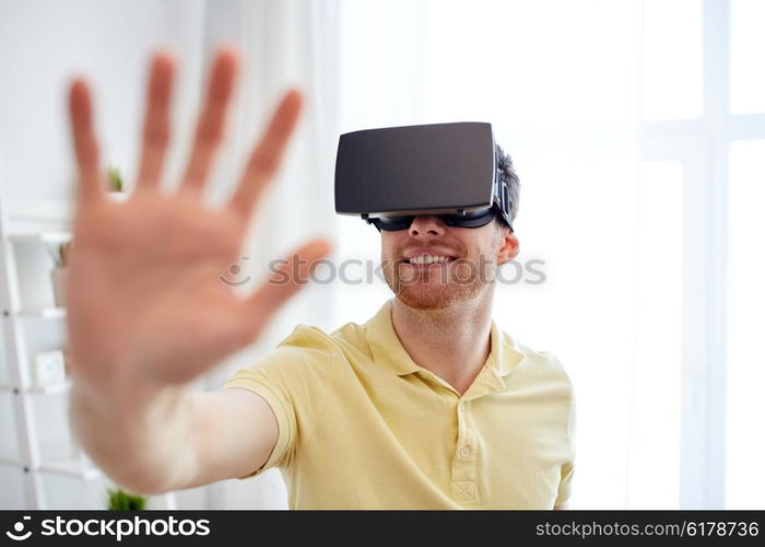 technology, gaming, entertainment and people concept - happy young man with virtual reality headset or 3d glasses playing video game