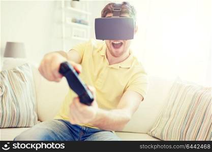 technology, gaming, entertainment and people concept - happy young man with virtual reality headset or 3d glasses with controller gamepad playing racing video game at home. man in virtual reality headset with controller