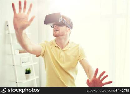 technology, gaming, entertainment and people concept - happy young man with virtual reality headset or 3d glasses playing video game at home. young man in virtual reality headset or 3d glasses