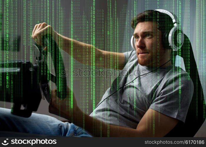 technology, gaming, entertainment and people concept - young man in headphones with pc computer playing car racing video game at home and steering wheel