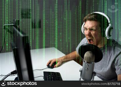 technology, gaming, entertainment, let&amp;#39;s play and people concept - angry screaming young man in headset with pc computer playing game at home and streaming playthrough or walkthrough video