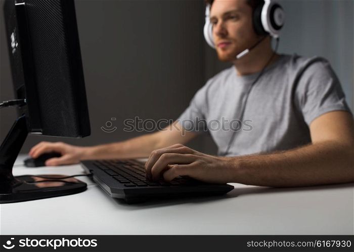 technology, gaming, entertainment, let&amp;#39;s play and people concept - close up of young man in headset with pc computer playing game at home and streaming playthrough or walkthrough video