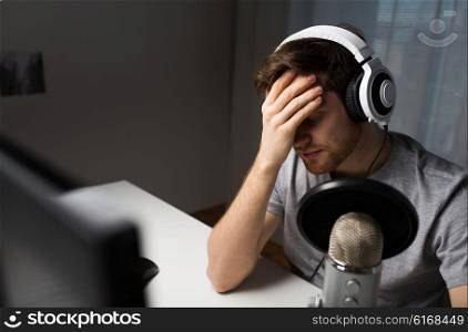 technology, gaming, entertainment, let&amp;#39;s play and people concept - close up of sad young man in headset with pc computer playing game at home and streaming playthrough or walkthrough video