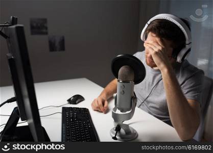 technology, gaming, entertainment, let&amp;#39;s play and people concept - close up of sad young man in headset with pc computer playing game at home and streaming playthrough or walkthrough video